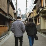 A young couple strolls through the traditional streets of Gion, Kyoto. Experience the serene ambiance and historic charm.